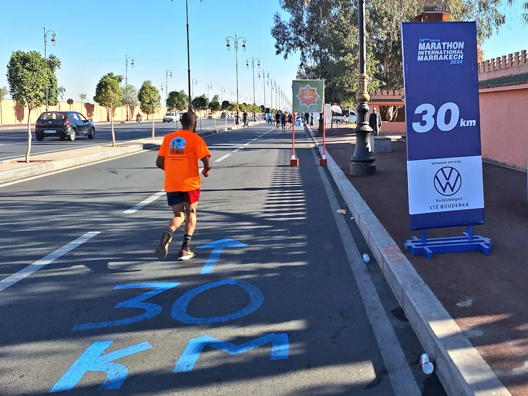Runner near 30km marker at Marrakech Marathon.