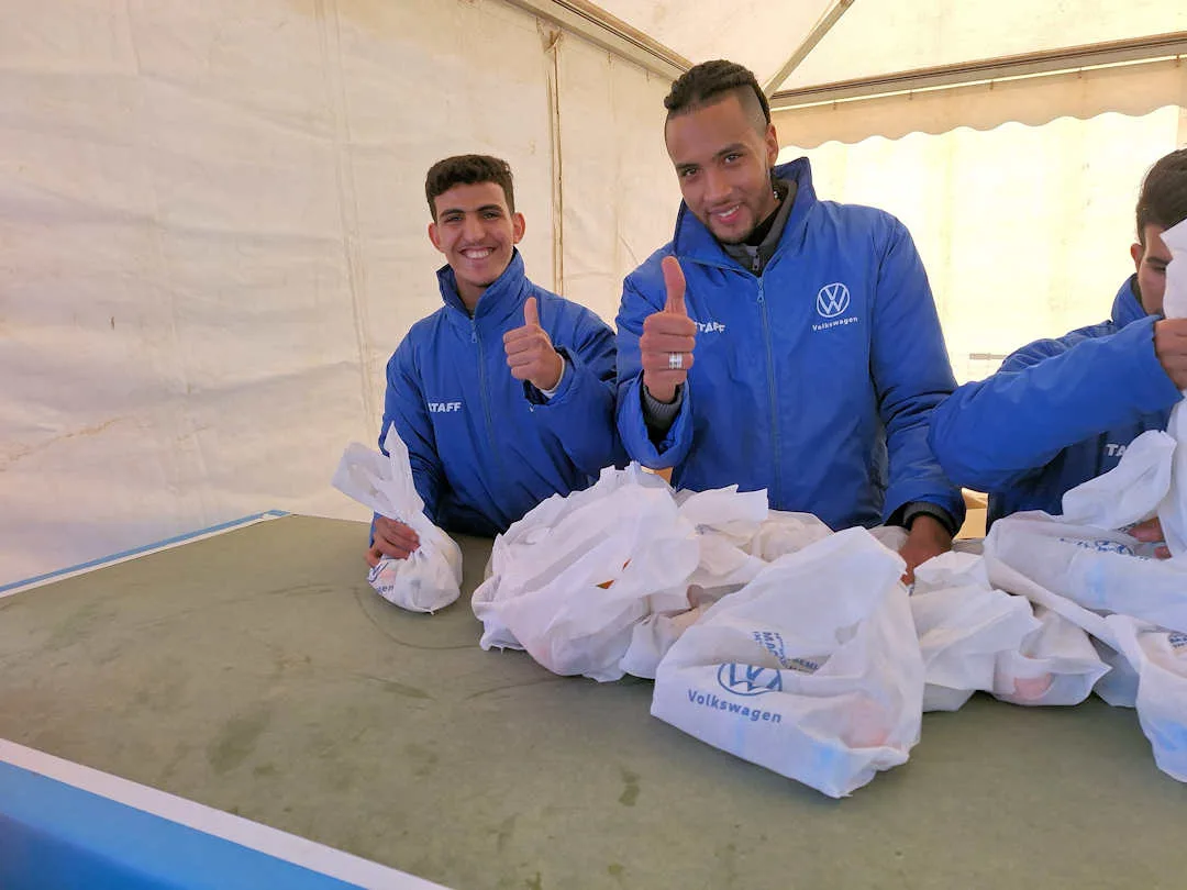 Marrakesh Marathon finish volunteers in Volkswagen jackets giving thumbs up in tent
